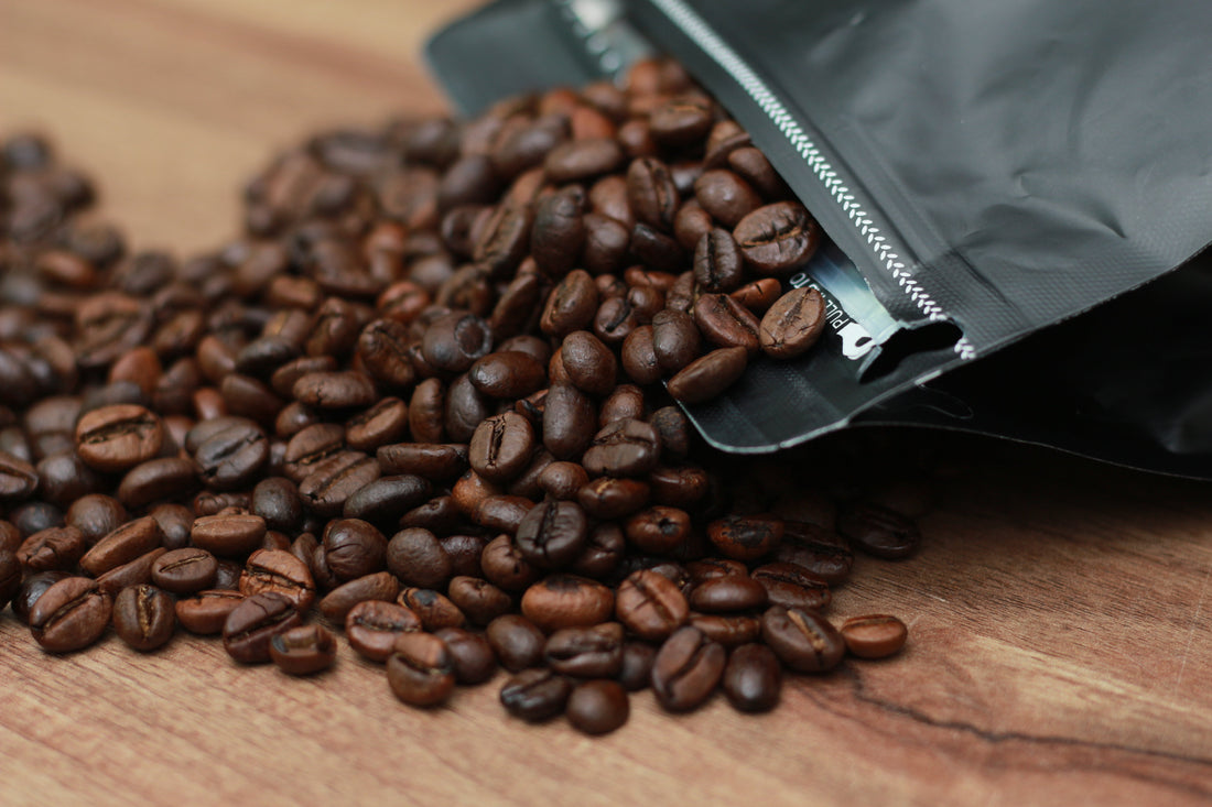 coffee pouch laying on table with coffee beans spilling out of it