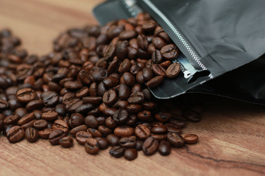 coffee pouch laying on table with coffee beans spilling out of it