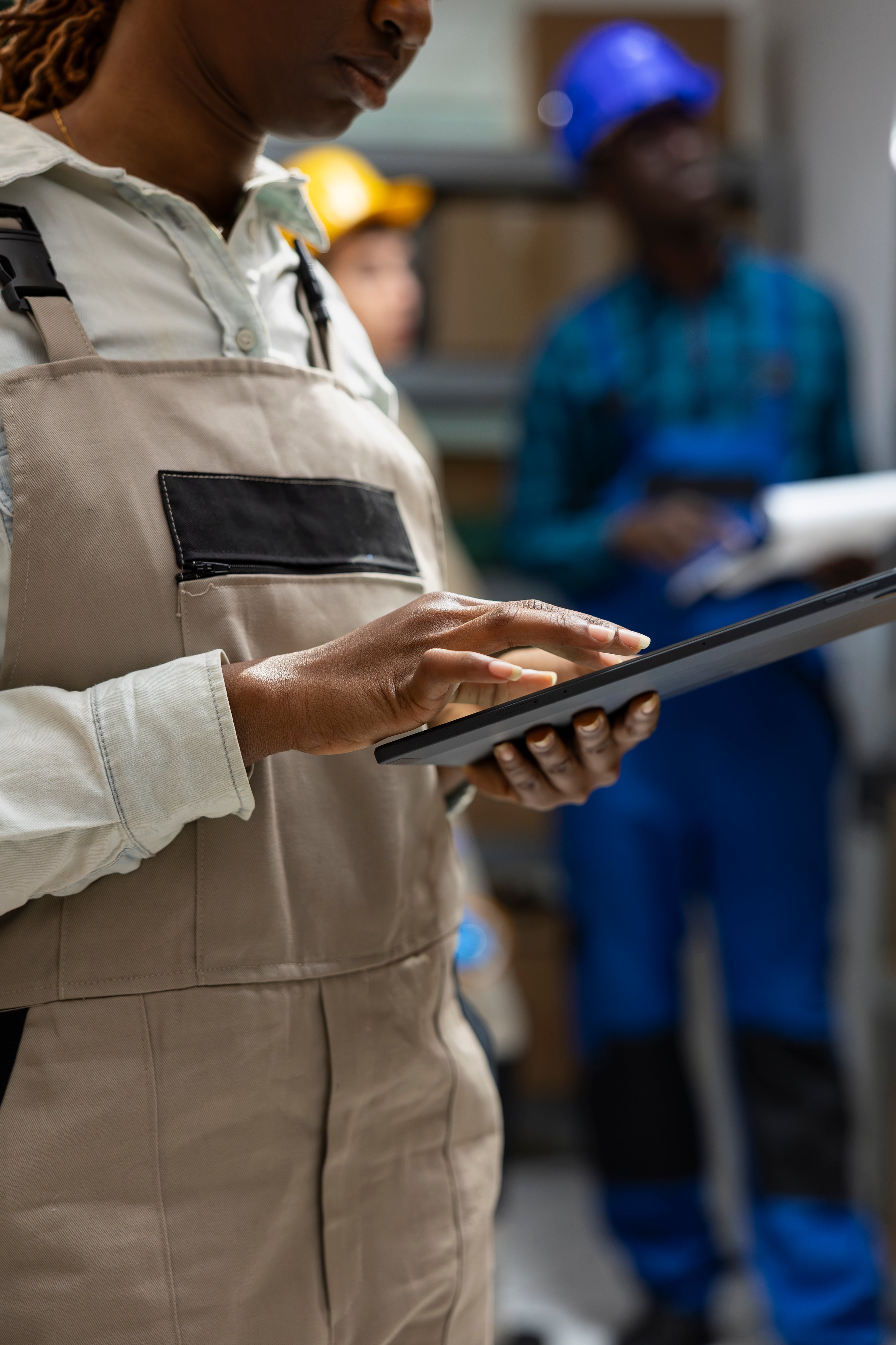 Person in beige work overalls using a tablet with blurred background