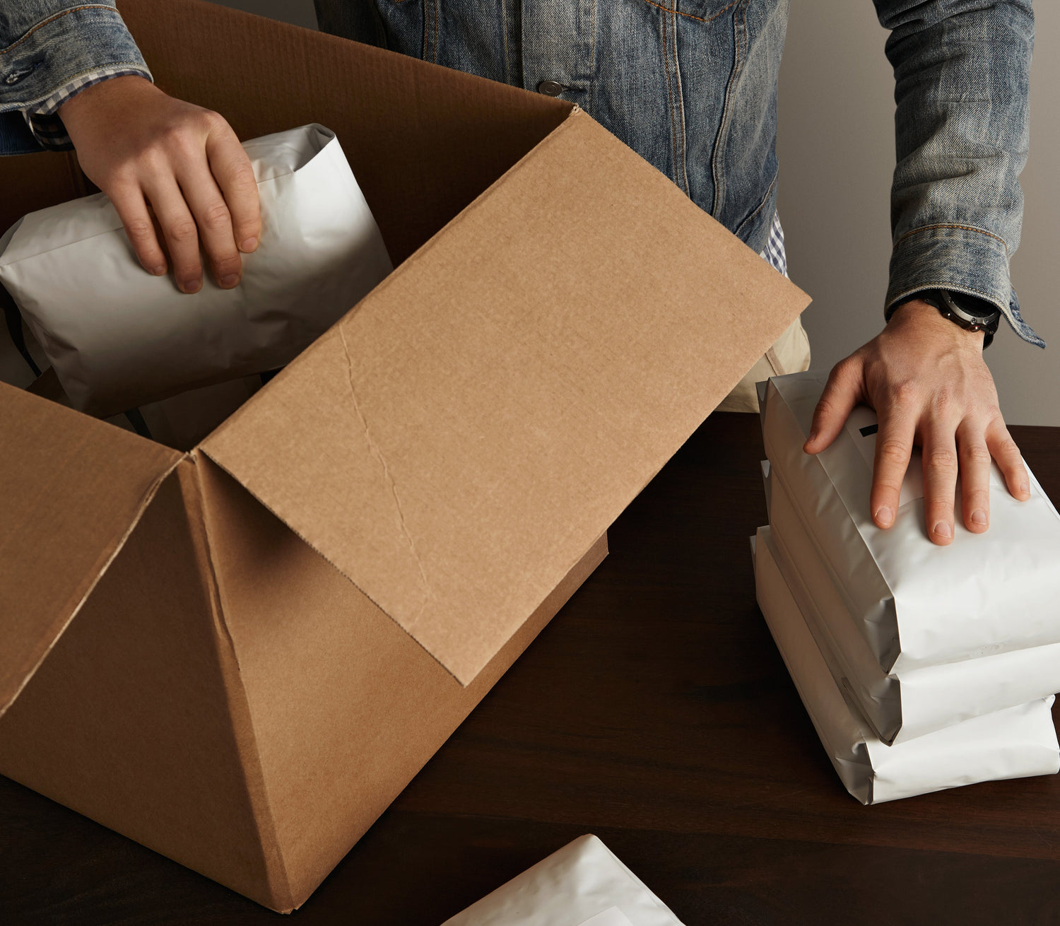 Person packing items into a cardboard box on a table