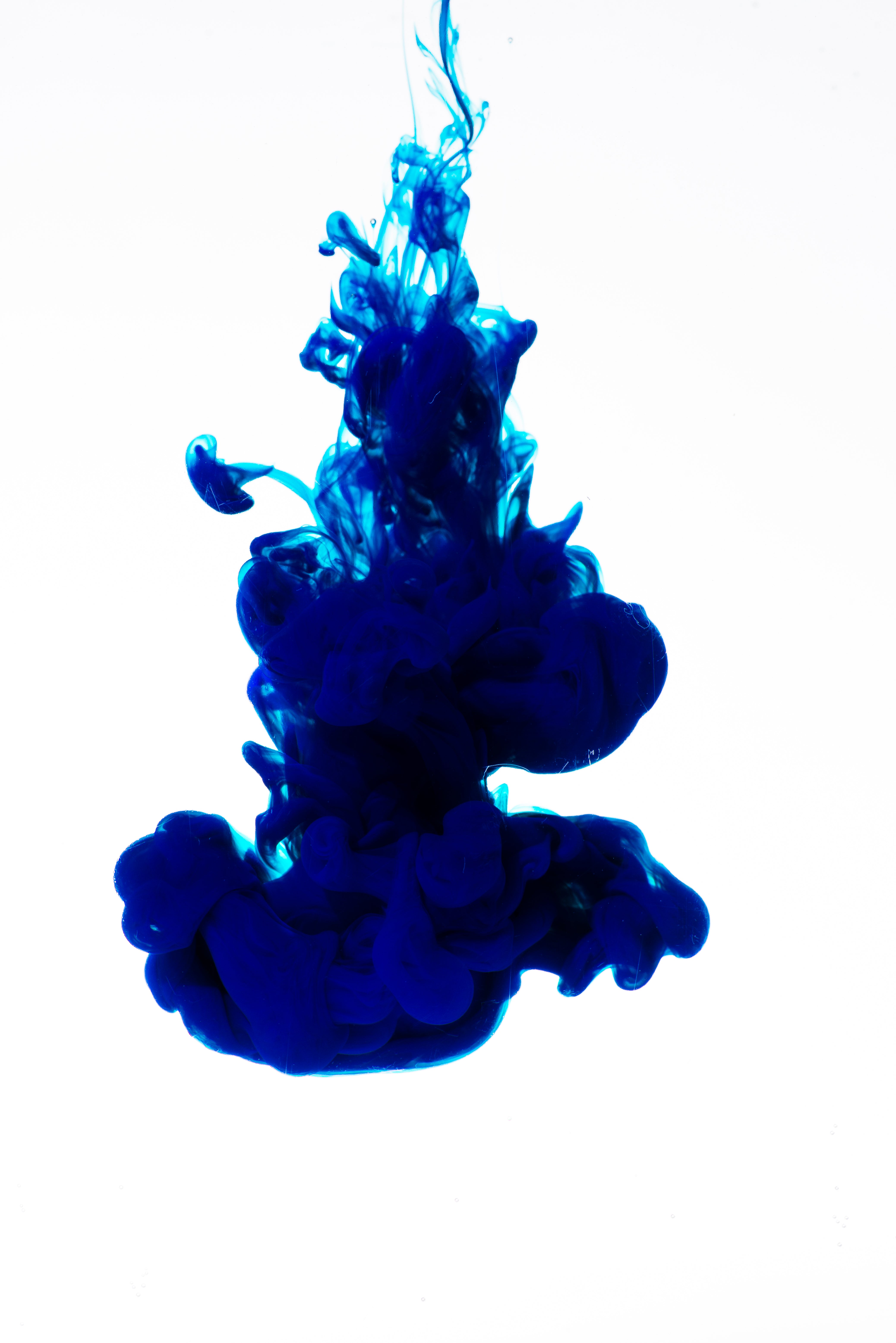 Blue ink droplets in water on a white background