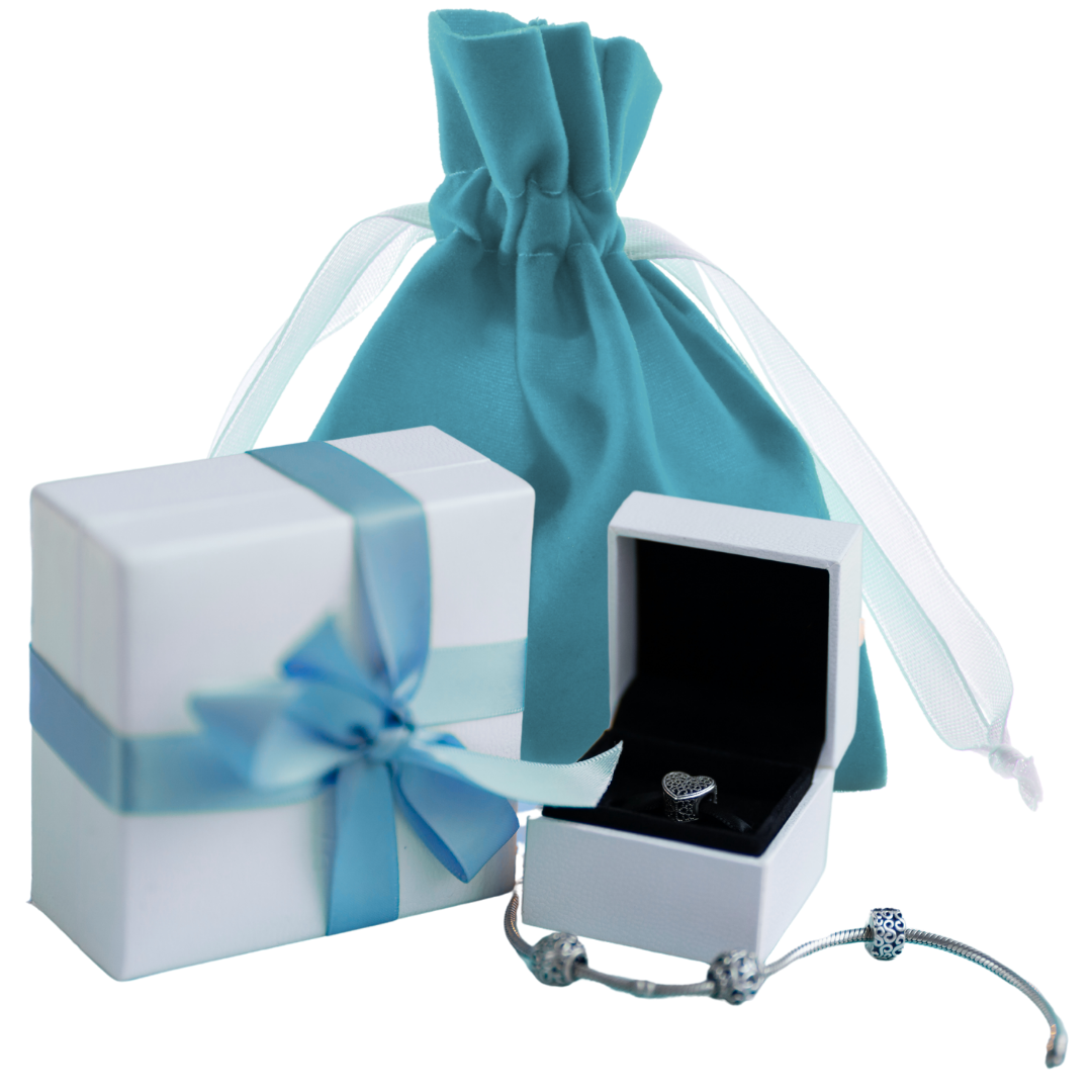 Silver bracelet and ring in an open jewelry box with a white gift box featuring a blue ribbon and a blue fabric gift bag. 